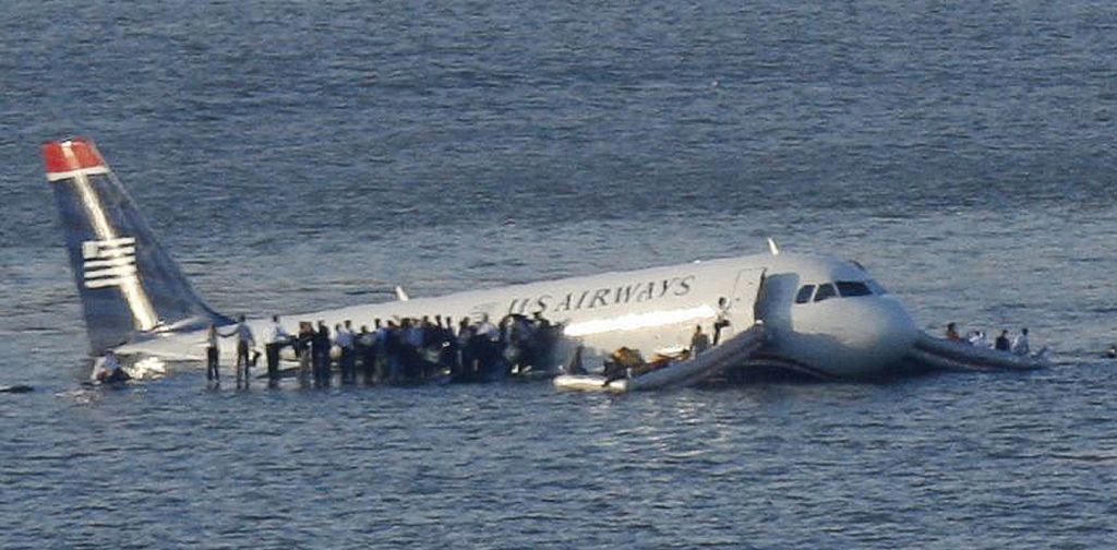 Passengers stand on the wings of a U.S. Airways plane as a ferry pulls up to it after it landed in the Hudson River in New York, January 15, 2009. Local media said the plane was an Airbus with 146 passengers and five crew which had just taken off from La Guardia Airport and was trying to return after apparently striking a flock of birds. REUTERS/Brendan McDermid (UNITED STATES) BEST QUALITY AVAILABLE - RTR23FP8